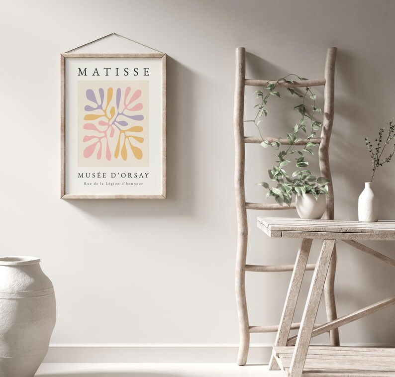 May include: A framed print with a colorful abstract design in pink, yellow, and purple. The print has the text "MATISSE" and "MUS&Eacute;E D'ORSAY" with the address "Rue de la L&eacute;gion d'honneur".