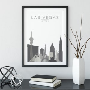 K&ouml;nnte beinhalten: Ein schwarzer gerahmter Druck mit wei&szlig;em Hintergrund und einer grauen Silhouette der Skyline von Las Vegas. Der Text "LAS VEGAS" und "NEVADA" ist in Grau unter der Skyline gedruckt.