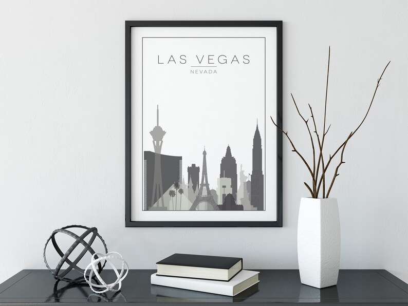 K&ouml;nnte beinhalten: Ein schwarzer gerahmter Druck mit wei&szlig;em Hintergrund und einer grauen Silhouette der Skyline von Las Vegas. Der Text "LAS VEGAS" und "NEVADA" ist in Grau unter der Skyline gedruckt.