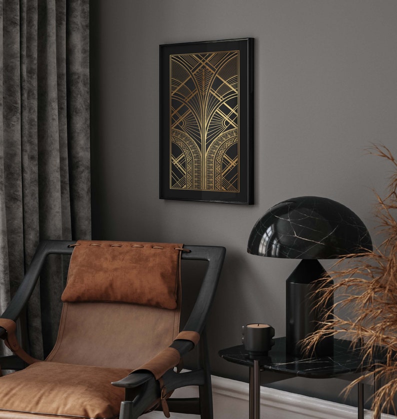 May include: A black framed print with a gold geometric design on a gray wall. A brown leather armchair with a brown pillow is in the foreground. A black marble lamp with a black base is on a black marble side table.