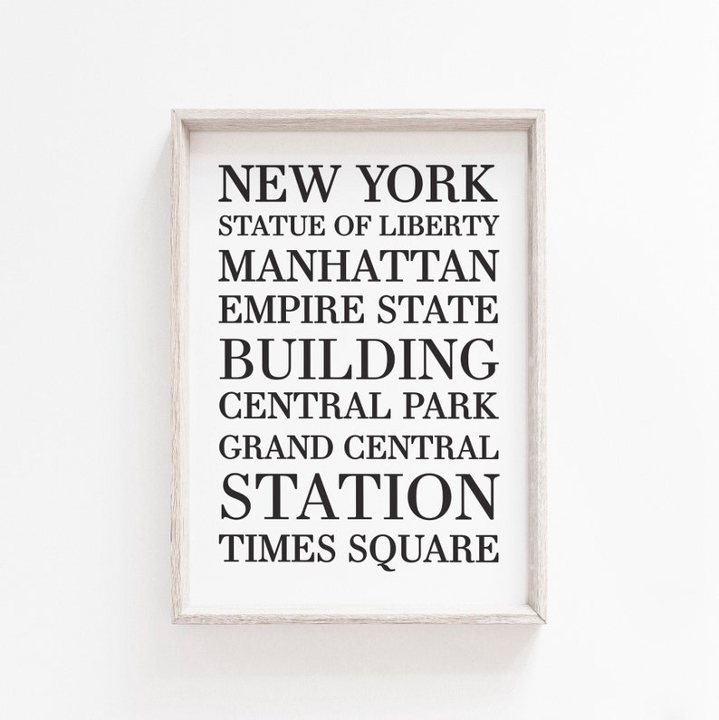 May include: A framed print with the text "NEW YORK" in black lettering, followed by a list of iconic New York City landmarks: Statue of Liberty, Manhattan, Empire State Building, Central Park, Grand Central Station, and Times Square.