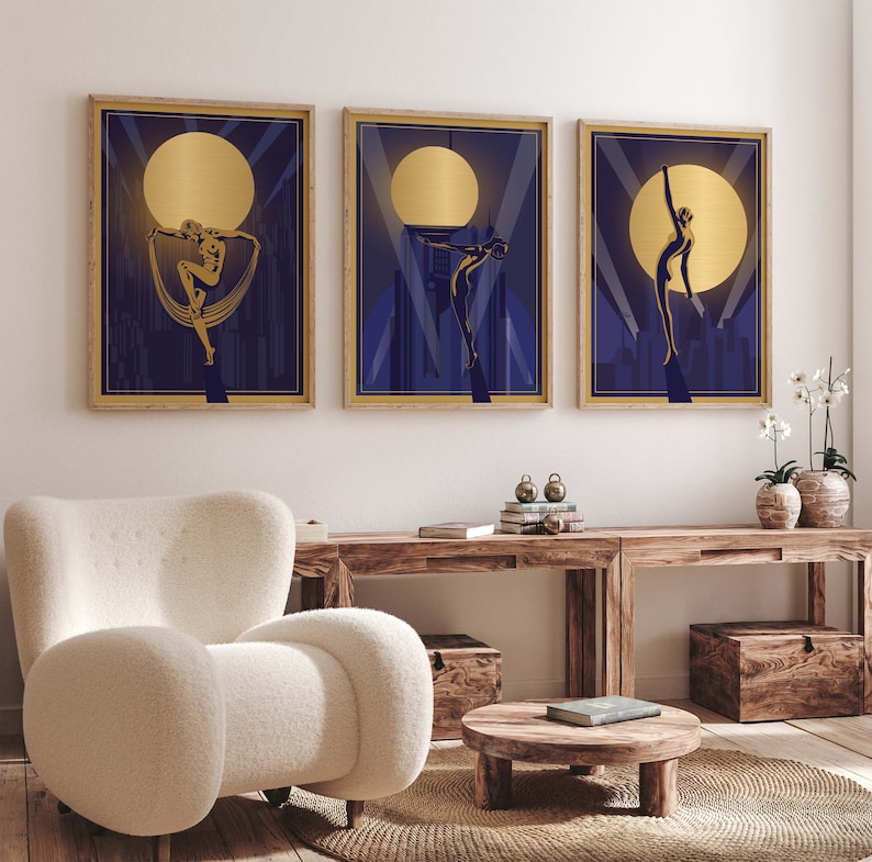 May include: Three framed art prints with a gold and blue color scheme. Each print features a silhouette of a woman in a stylized pose against a backdrop of a city skyline and a large, golden moon.