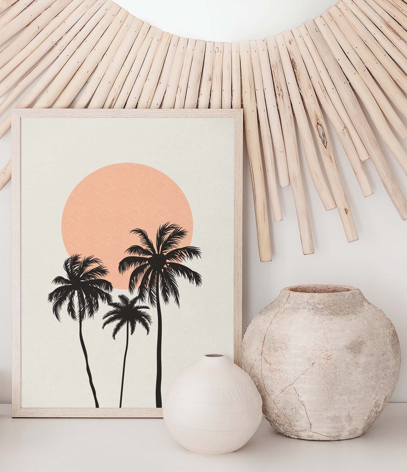 May include: A framed print with a minimalist design featuring three palm trees silhouetted against a peach-colored sun on a beige background.