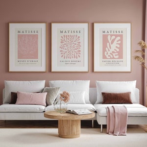 May include: Three framed art prints with a pink background and white line drawings of abstract floral designs. The prints are titled "Matisse" and feature the text "Mus&eacute;e d'Orsay", "Galerie Boh&egrave;me", and "Papier D&eacute;coup&eacute; Collection".