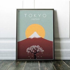 Puede incluir: Un p&oacute;ster minimalista con un esquema de color azul, rojo y amarillo. El p&oacute;ster presenta una imagen estilizada del Monte Fuji, un &aacute;rbol de cerezo en flor y el texto "TOKYO JAPON".