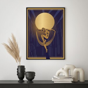 May include: A gold silhouette of a woman dancing against a blue and gold background with a large gold moon.