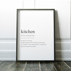 May include: A black and white framed print with the word "kitchen" defined as "the heart of our home. A gathering place where all family and friends are welcome. Where deliciousness is created and precious memories are made."