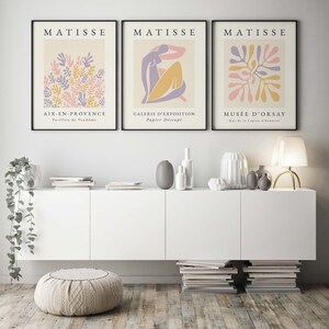 May include: Three framed art prints with a minimalist design featuring abstract shapes in pink, yellow, and purple. The prints are titled "MATISSE" and each features a different location: "AIX-EN-PROVENCE", "GALERIE D'EXPOSITION", and "MUS&Eacute;E D'ORSAY".