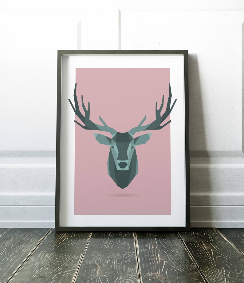May include: A framed print of a geometric deer head design in shades of teal and gray on a pink background.