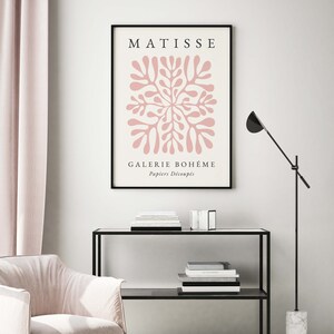May include: A black framed poster with the text "MATISSE" and "GALERIE BOHEME" in white. The poster features a pink abstract design with the text "Papiers D&eacute;coup&eacute;s" in white.