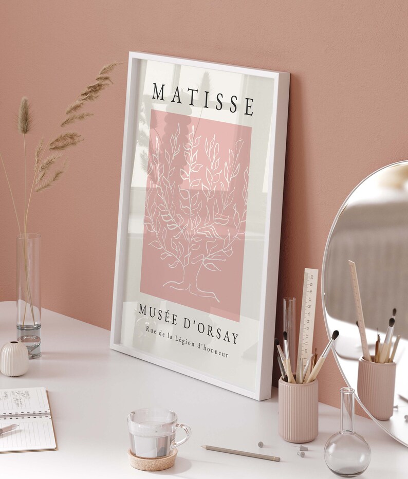 May include: A white framed print with a pink background and a white line drawing of a tree. The text "MATISSE" is at the top of the print and "MUS&Eacute;E D'ORSAY" is at the bottom with the address "Rue de la L&eacute;gion d'honneur".