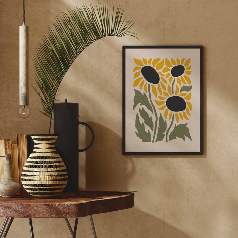 May include: A framed print of three stylized sunflowers in yellow and green on a cream background. The sunflowers have black centers and are arranged in a cluster.