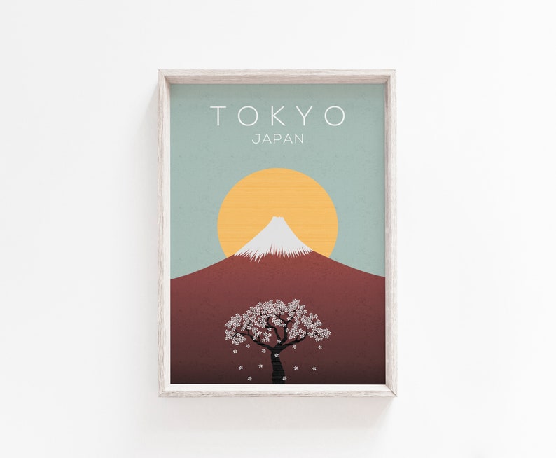 Puede incluir: Una impresi&oacute;n enmarcada con un dise&ntilde;o minimalista que presenta una imagen estilizada del Monte Fuji, un &aacute;rbol de cerezo en flor y un sol amarillo sobre un fondo azul y marr&oacute;n. El texto "TOKYO JAP&Oacute;N" est&aacute; impreso en la parte superior de la impresi&oacute;n.