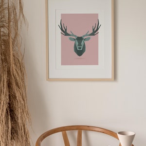 May include: A framed print of a geometric deer head illustration on a pink background. The deer is a dark green color with antlers.