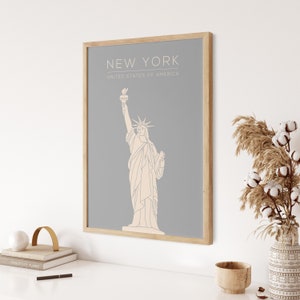 May include: A framed print with a grey background and a line drawing of the Statue of Liberty. The text "NEW YORK" and "UNITED STATES OF AMERICA" is printed in white below the image.