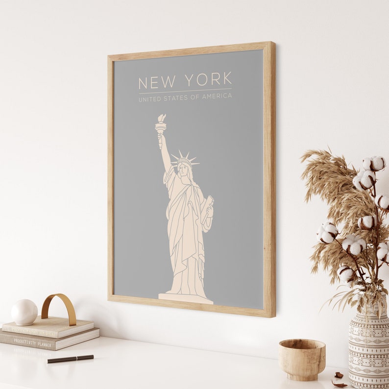 May include: A framed print with a grey background and a line drawing of the Statue of Liberty. The text "NEW YORK" and "UNITED STATES OF AMERICA" is printed in white below the image.