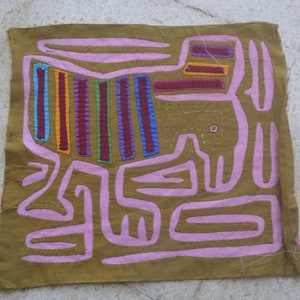 May include: A square of brown fabric with a pink and multi-coloured design stitched onto it. The design is abstract and resembles a stylised animal.