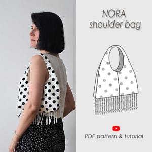 Könnte beinhalten: Eine weiße Umhängetasche mit schwarzen Punkten und einer Fransenborte am unteren Rand. Das Bild enthält eine technische Strichzeichnung der Tasche mit der Aufschrift NORA shoulder bag und den Text PDF pattern & tutorial mit einem roten YouTube-Symbol.