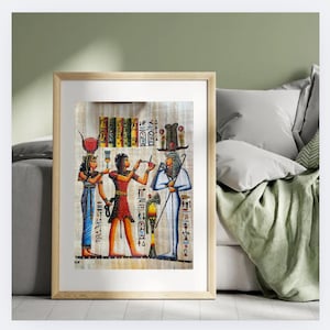 May include: Framed artwork depicting ancient Egyptian figures in vibrant colors. The artwork features hieroglyphs and detailed illustrations of people in traditional attire. The frame is a light wood color, adding a classic touch to the piece.