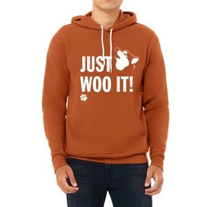 May include: A rust-colored hoodie with a white paw print and the text "JUST WOO IT!" with a white silhouette of a dog's head howling.