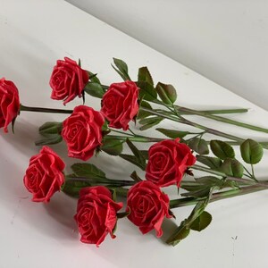 May include: A bouquet of eight red roses with green stems and leaves.