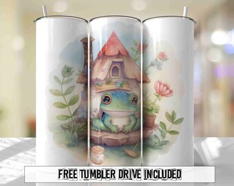 May include: A white tumbler with a whimsical illustration of a frog sitting in front of a small house with a red roof. The house is surrounded by green plants and flowers. The tumbler has the text "Free Tumbler Drive Included" printed on the bottom.