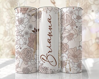 May include: A floral-themed tumbler with a white background and a pattern of brown and beige flowers. The name "Brianna" is written in a brown script font on the center tumbler. The tumbler includes a straw.