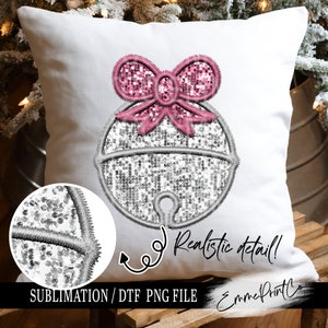 May include: A white pillow with a silver sequin bell with a pink sequin bow. The text "Realistic detail!" is written on the pillow. The text "Sublimation/ DTF PNG File" is written below the bell. The text "EmmePrintCo" is written in the bottom right corner of the pillow.