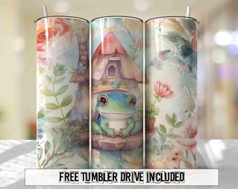 May include: A set of three stainless steel tumblers with a whimsical design featuring a frog sitting in front of a small cottage with a pink roof. The background is a watercolor-style floral pattern with pink roses, green leaves, and blue flowers.