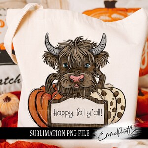 Puede incluir: Una bolsa de tela blanca con un diseño de una vaca Highland marrón y blanca con la nariz rosa sosteniendo un cartel que dice "Happy fall y'all!" La vaca está rodeada de calabazas. La imagen está en una bolsa de tela blanca con las palabras "Sublimation PNG File" y "Emme Print Co." en la parte inferior.