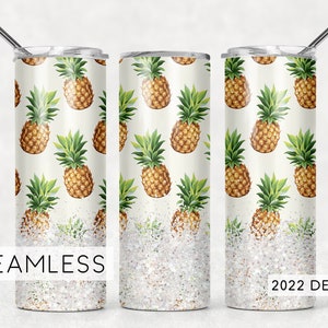 May include: A white stainless steel tumbler with a white glitter bottom. The tumbler features a seamless pattern of pineapple illustrations. The text "2022 DESIGN" is printed on the bottom right corner of the image.