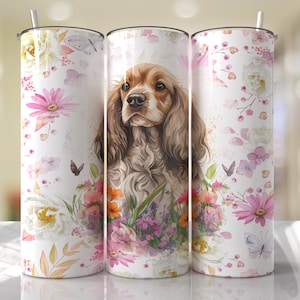 Könnte beinhalten: Ein weißer Becher mit einem Blumenmuster und einer Aquarell-Illustration eines braunen und weißen Cocker Spaniels. Der Becher hat ein rosa, weißes und grünes Blumenmuster mit Schmetterlingen.