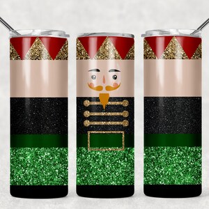 Op de afbeelding: Een roestvrijstalen tumbler met een notenkrakerontwerp. De tumbler heeft een rood, goud, zwart en groen glitterpatroon.