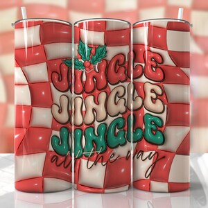 Peut inclure: Un gobelet de 590 ml avec un motif à carreaux rouges et blancs. Le gobelet présente le texte "Jingle Jingle Jingle all the way" dans une police rétro, avec des accents de houx. Une paille blanche est visible.