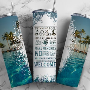 May include: A white tumbler with a blue and white tropical beach scene. The tumbler has text that reads "Swimming Pool Rules: Soak Up The Sun, Relax Unwind, Laugh Play, Make Memories, No Running Pushing Peeing, Wear Your Sunscreen, Good Friends Always, Welcome".