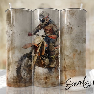 May include: A stainless steel tumbler with a design of a motocross rider on a dirt bike. The background is a distressed, brown and gray color.