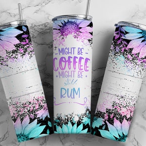 Op de afbeelding: Een witte tumbler met een bloemenontwerp en de tekst "Might be coffee, might be rum". De tumbler heeft een zwart deksel en een rietje.