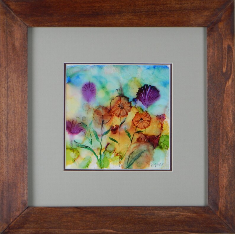 May include: A framed abstract watercolor painting of a field of flowers in shades of purple, orange, and yellow. The flowers are painted in a loose, expressive style, and the background is a soft blue.