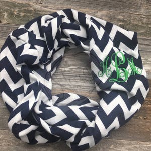 May include: A navy blue and white chevron infinity scarf with the monogram "HBM" embroidered in green.