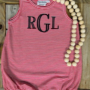 Op de afbeelding: Rode en witte gestreepte, mouwloze baby romper met de letters "RGL" in zwart geborduurd op de voorkant.