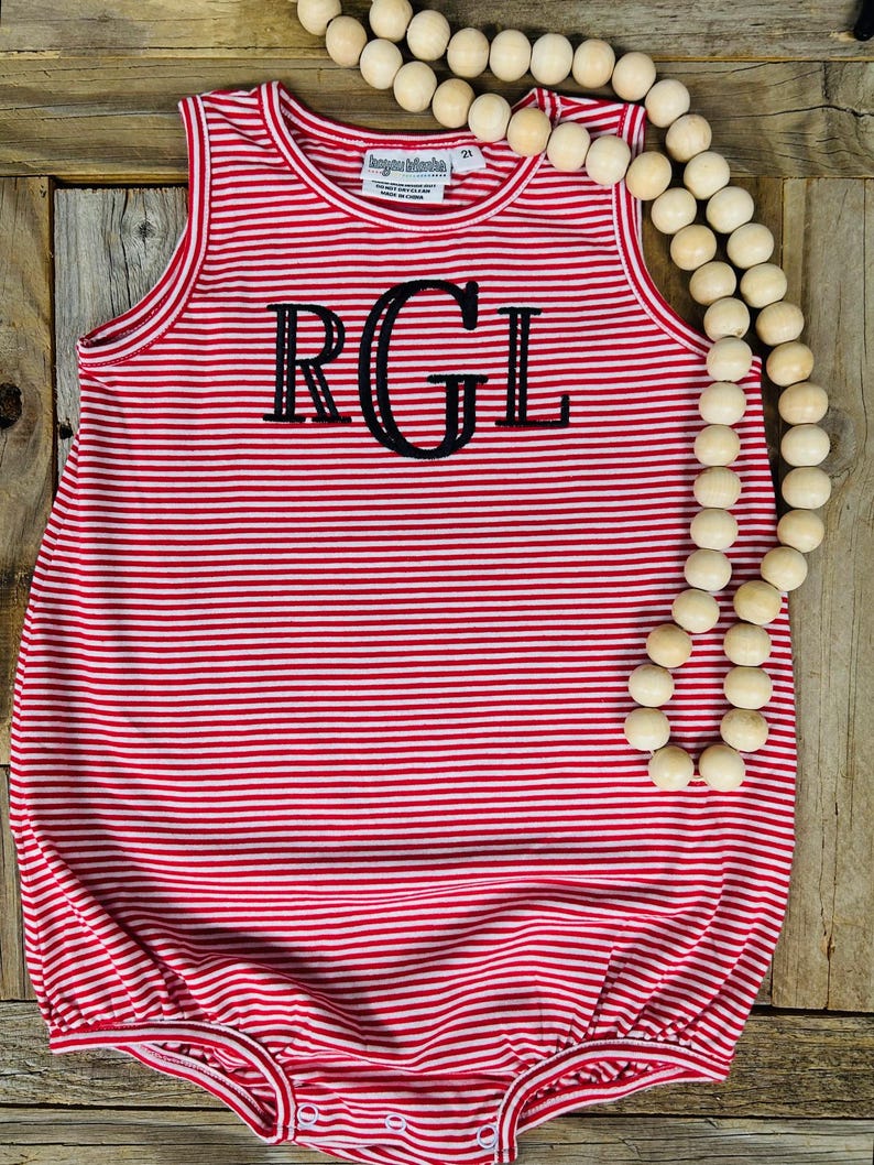 Op de afbeelding: Rode en witte gestreepte, mouwloze baby romper met de letters "RGL" in zwart geborduurd op de voorkant.