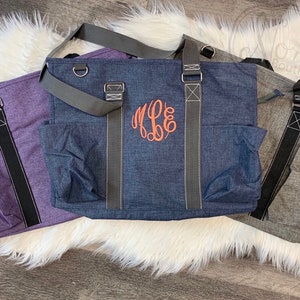 May include: Three tote bags in different colors: purple, blue, and gray. The blue bag has a monogram on the front that says "M.E.B."