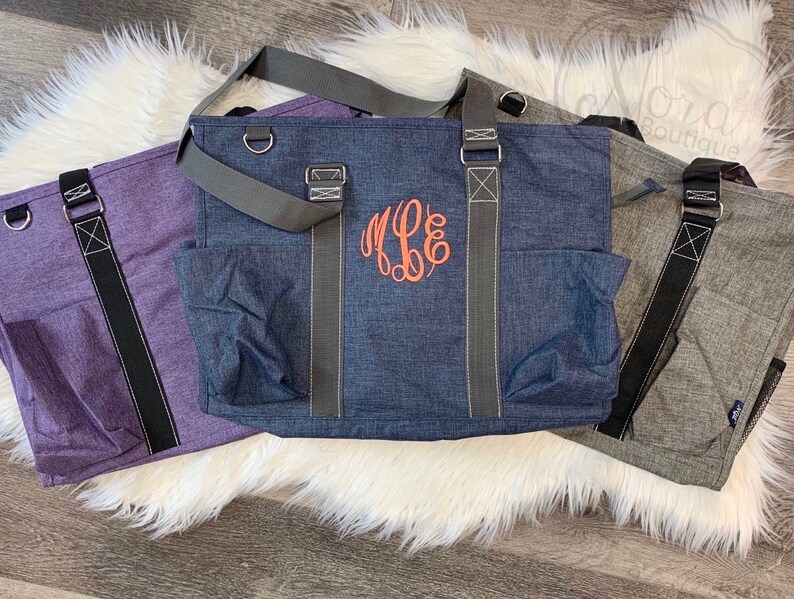 May include: Three tote bags in different colors: purple, blue, and gray. The blue bag has a monogram on the front that says "M.E.B."