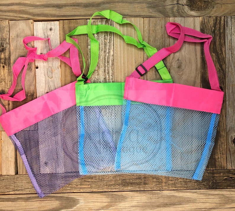May include: Three mesh bags with pink, green, and blue trim. The bags have adjustable straps and are made of a fine mesh material.