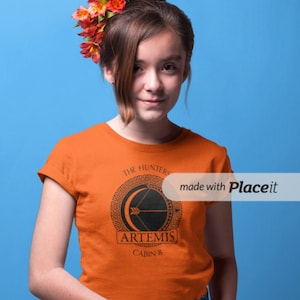 May include: Orange t-shirt with a black graphic featuring a bow and arrow inside a circle, with the text "The Hunters of Artemis" and "Cabin 8". The shirt is worn by a person with flowers in their hair and a blue skirt.