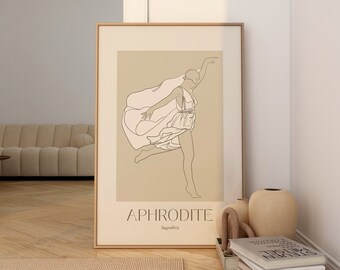 May include: A framed art print featuring a line drawing of a woman in a flowing dress, with the word "APHRODITE" below. The artwork is in a gold frame and set against a beige background. The print is displayed in a room with a beige rug and a beige sofa.