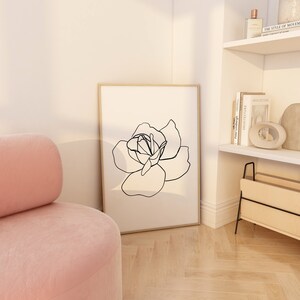 Puede incluir: Un dibujo en blanco y negro de una rosa en un estilo simple y moderno. El dibujo est&aacute; enmarcado y colgado en una pared blanca.