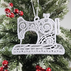 Peut inclure: Ornement de Noël en forme de machine à coudre en dentelle blanche. L'ornement est détaillé avec des dentelles complexes et a une boucle pour l'accrocher.
