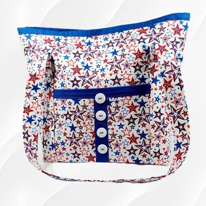 Puede incluir: Una bolsa de mano de color azul y rojo con estampado de estrellas y cierre de botón azul y blanco. La bolsa tiene una correa larga para llevarla al hombro.