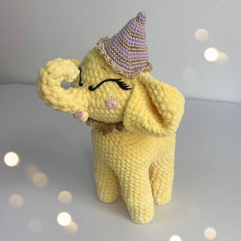 a yellow stuffed elephant with a purple hat